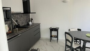A compact kitchen with a microwave, sink, and a small table with chairs.
