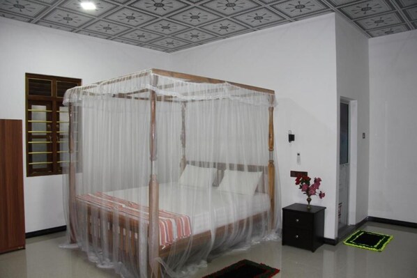 Una habitación con una cama con dosel, una mesita de noche con un florero y un techo con diseño geométrico.