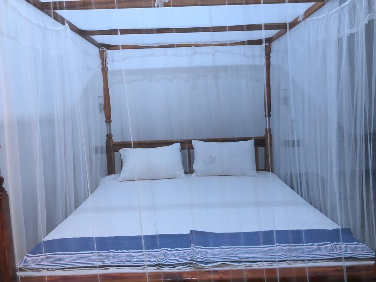 A bed with a canopy and white bedding.