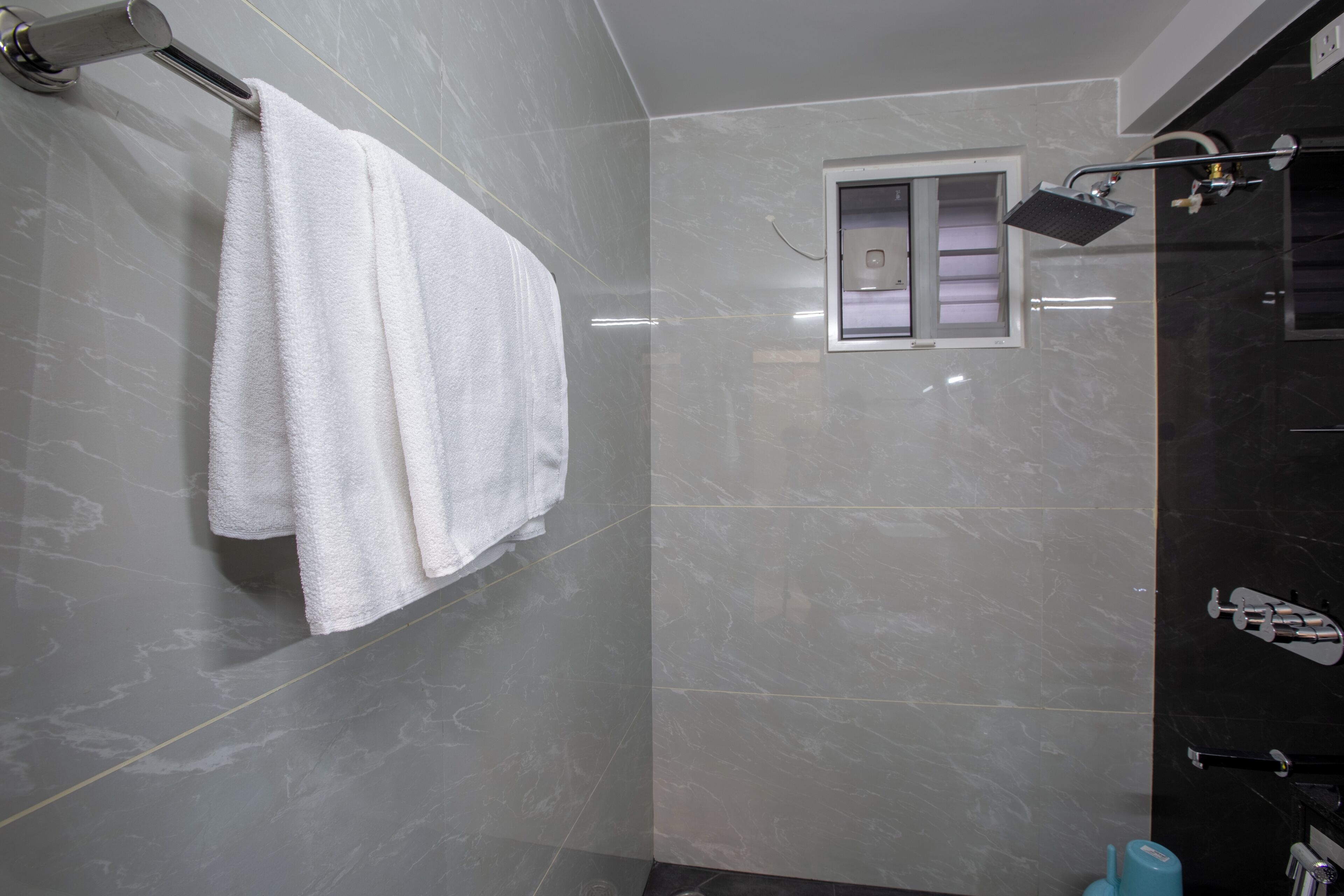 Un baño moderno con un espejo grande, un perchero y una ducha con cabezal de ducha manual.