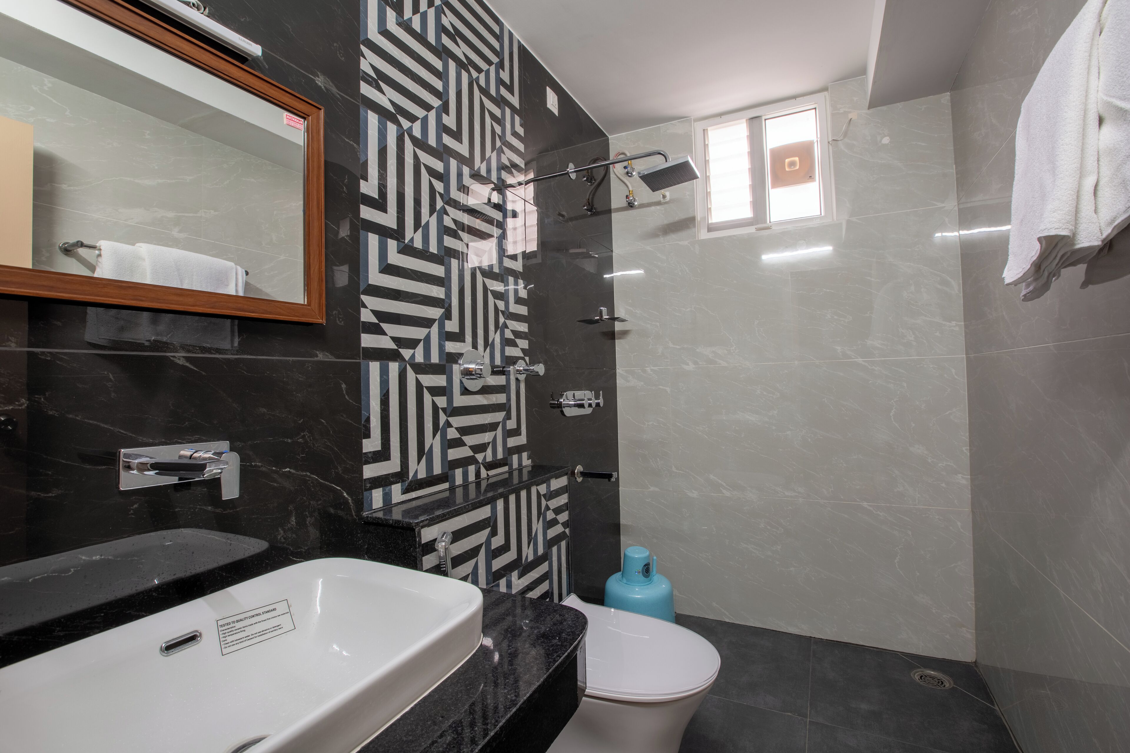 Un baño moderno con pared estampada en blanco y negro, un lavamanos blanco y un inodoro.