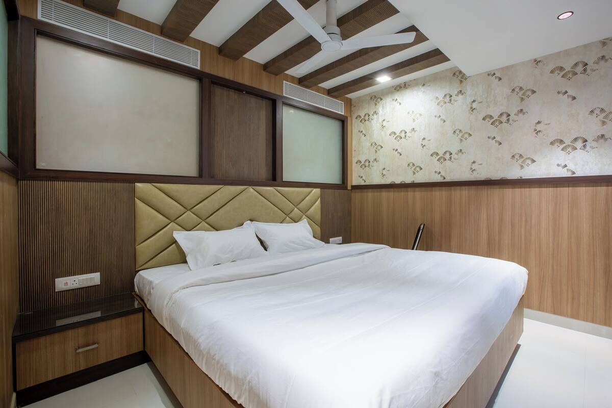 Un dormitorio moderno con una cama grande, paneles de madera, un ventilador de techo y un equipo de aire acondicionado montado en la pared.