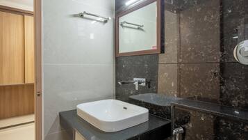 A modern bathroom with a white sink, a mirror, and a marble wall.