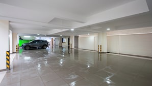 A spacious, clean indoor parking area with a shiny tiled floor and a parked car. - Hotel PRM Aruna Archadia (Erode)