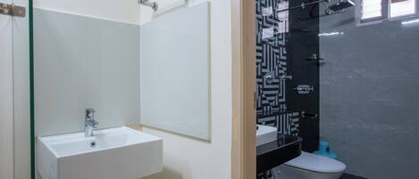 A modern bathroom with a white sink, a large mirror, a black and white patterned shower wall, and a toilet.