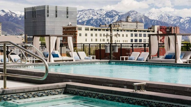 A pool with lounge chairs and a view of snow-capped mountains in the background.