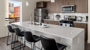 A modern kitchen with a large island, stainless steel appliances, and a view of the city.