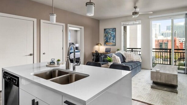 A modern kitchen with a large island, a dining area with a sofa, and a balcony with a city view.