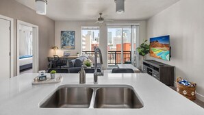A modern kitchen with a large island, double sinks, and a dining area with a view of the city.