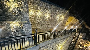 Un escalier en pierre avec des rampes métalliques menant à un niveau supérieur.