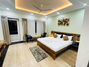 A hotel room with a bed, a ceiling fan, a desk, a chair, and a window with curtains.