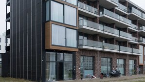 Un immeuble à plusieurs étages doté d’une architecture moderne, avec de grandes fenêtres et des balcons.