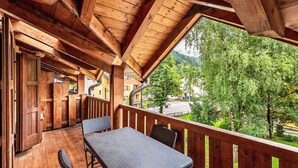 Ein Holzbalkon mit Tisch und Stühlen, mit Blick auf eine Stadt und Grünflächen.