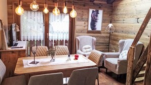 Ein gemütliches Holzinterieur mit einem Esstisch, Stühlen und Pendelleuchten.