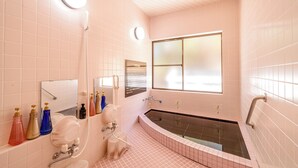 Ein Badezimmer mit einer großen Badewanne, einem Spiegel und einem Fenster.