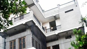 A modern multi-story building with a covered parking area. - Comfort Cottage By GRB (Varanasi)