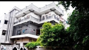 A multi-story building with balconies and a gated entrance. - Comfort Cottage By GRB (Varanasi)