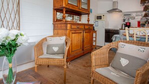 Una cucina accogliente con mobili in vimini, un armadietto in legno e un vaso di fiori bianchi.
