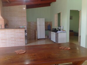 Una cocina con horno de ladrillo, refrigerador blanco y mesa de madera.