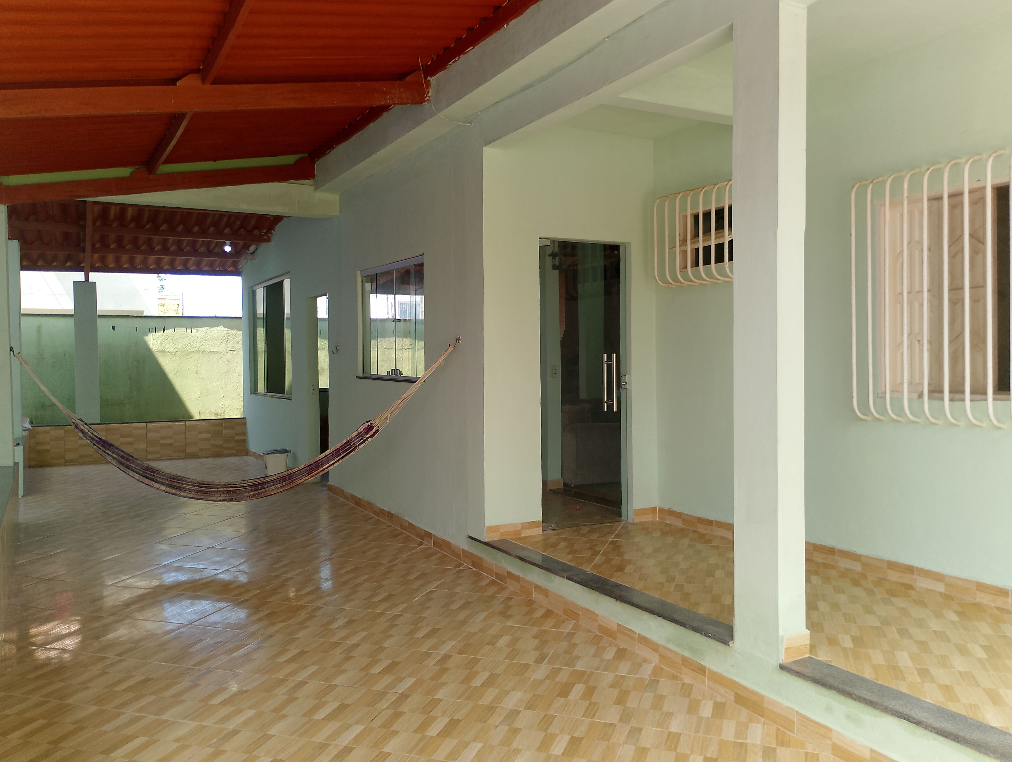 A room with a hammock, a glass door, and a tiled floor.