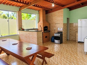 Cozinha com parede de tijolos, fogão a gás, forno embutido e geladeira.