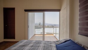 Et soveværelse med en seng, en skydedør til en balkon og en trædør.