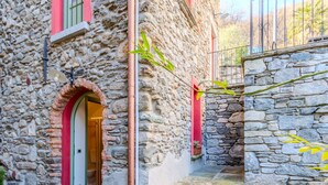 A stone building with a red door and a small balcony. - Tuschaus by Interhome (Domaso)