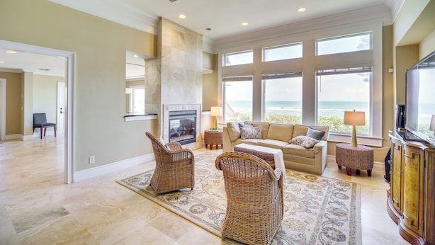 A spacious living room with a fireplace, large windows, and a view of the ocean.