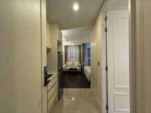 A hotel room with a bed, a sofa, a TV, and a minibar. - Xiyun Holiday Apartment Pattaya (Sattahip)