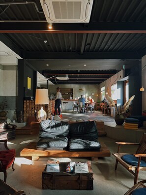 A spacious lounge area with a leather sofa, wooden coffee table, and wicker chairs. - Lemonsea Onomichi (Onomichi)