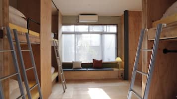 Una habitación con literas, una ventana con persianas, una escalera y un aire acondicionado instalado en la pared.