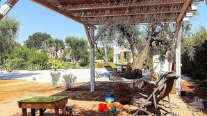 A covered outdoor area with a wooden table, a hammock, and a slide.