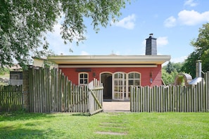 Een rode gebouw met een houten omheining, schoorsteen en heldere lucht.