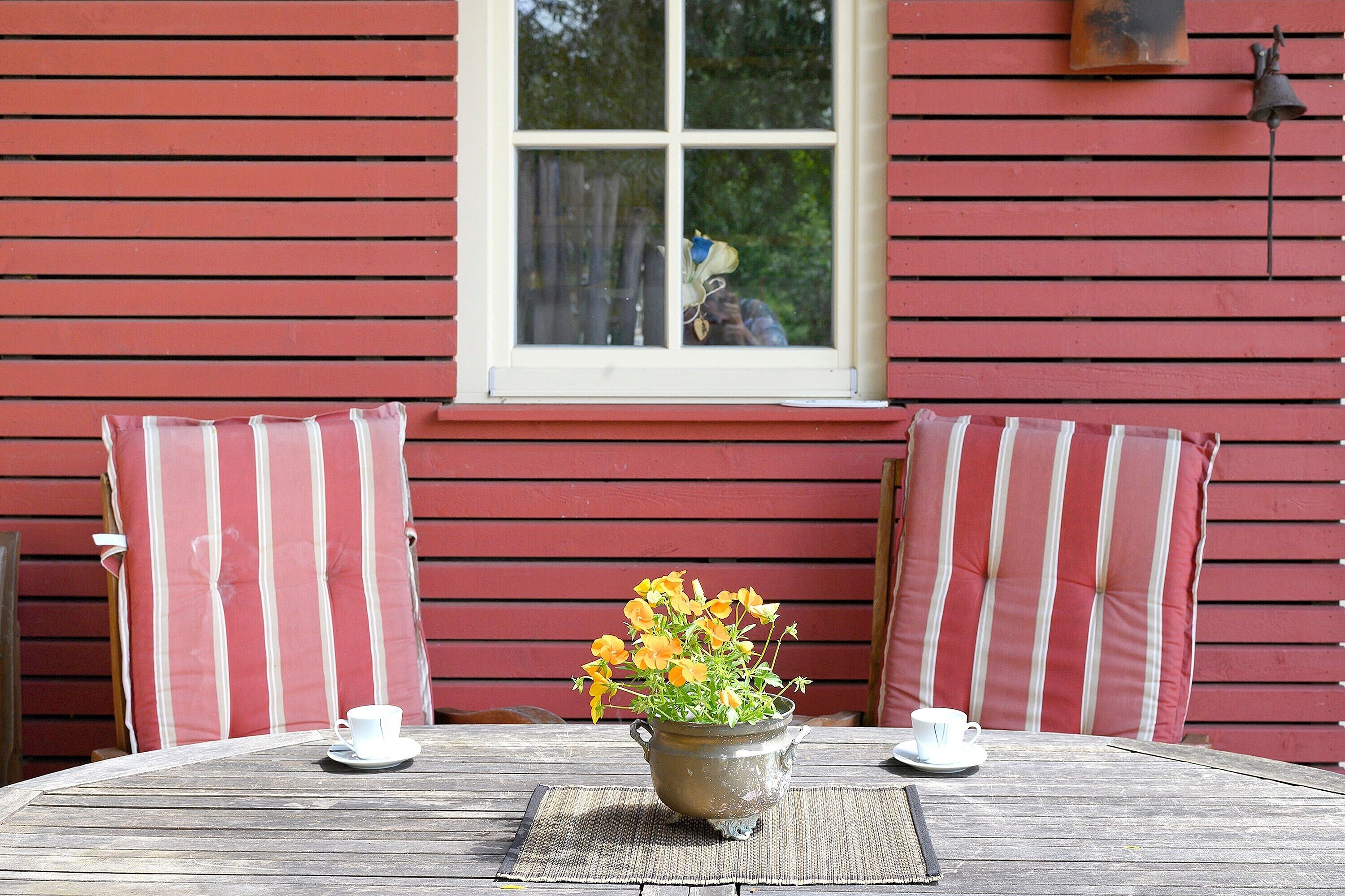 A wooden table with two white cups and a flower pot.