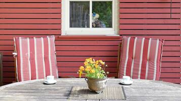 A wooden table with two white cups and a flower pot.