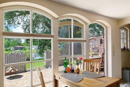 A dining area with a view of a backyard, a brick wall, and a wooden fence.. Holiday Home 'Reiseoase' with Lake View, Wi-Fi and Air Conditioning