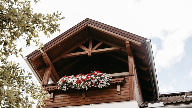 A wooden building with a balcony and a flower arrangement. - Room 'Seifterhof - Double Room' with Mountain View, Shared Terrace and Wi-Fi (Sankt Andrä im Lungau)