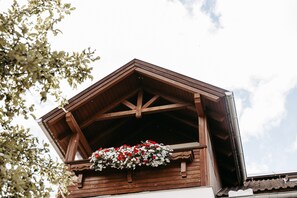 Een houten gebouw met een balkon en een bloemstuk.