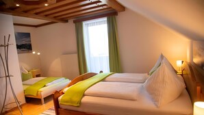 A bedroom with two beds, a window with curtains, a radiator, and a wooden ceiling. - Room 'Seifterhof - Double Room' with Mountain View, Shared Terrace and Wi-Fi (Sankt Andrä im Lungau)