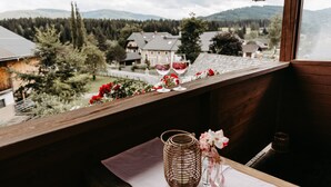 Un balcón con vistas a un pueblo, una cesta de mimbre y dos copas de vino.