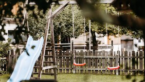 Un parque infantil con tobogán, columpios y una cerca de madera.