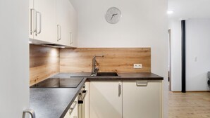 Una cucina moderna con zoccolo in legno, elettrodomestici in acciaio inossidabile e un orologio a parete.