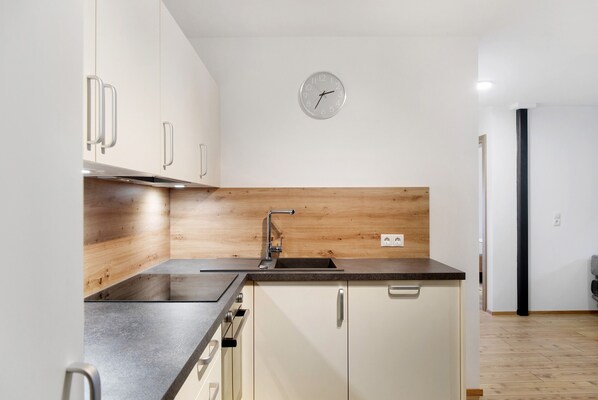 Una cocina moderna con salpicadero de madera, electrodomésticos de acero inoxidable y un reloj de pared.