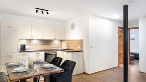 Una cucina moderna con zona pranzo, pavimento in legno e orologio a parete.