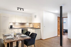 A modern kitchen with a dining area, wooden flooring, and a clock on the wall. - Apartment 'Ben's Auszeit Top 4' with Private Garden and Wi-Fi (Umhausen)