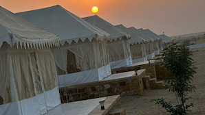 A row of tents with a stone foundation, set against a sunset backdrop. - Raghav Resort Jaisalmer (Jaisalmer)