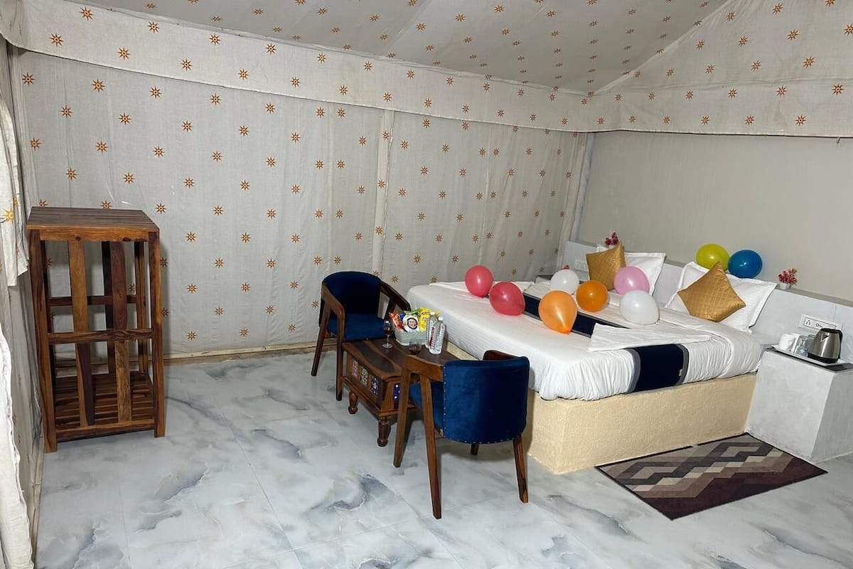 A bedroom with a bed, a wooden chair, a small table, and balloons.