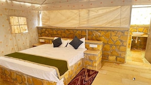 A bedroom with a stone wall bed, a stone bench, a small sink, and a window with a view. - Raghav Resort Jaisalmer (Jaisalmer)