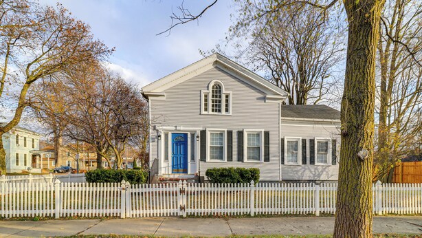 A two-story house with a white picket fence, a blue front door, and a small front porch. - 1 Block to Downtown Adrian: Spacious Home! (Adrian)