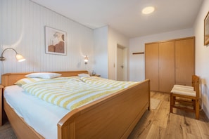 Ein Schlafzimmer mit einem hölzernen Bett, Nachttischlampen, einem Sessel und einem Kleiderschrank.